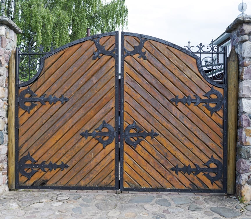 Custom wooden driveway gate with ornamental wrought-iron scrollwork