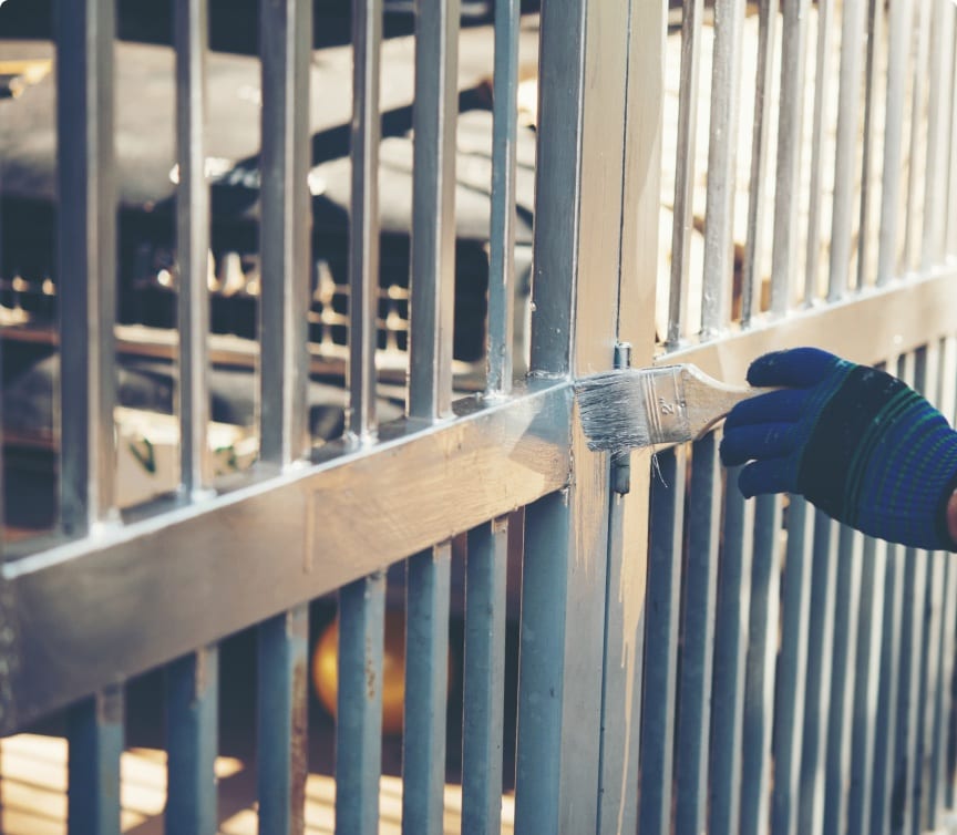 Gloved worker refinishing a metal fence rail during a repair