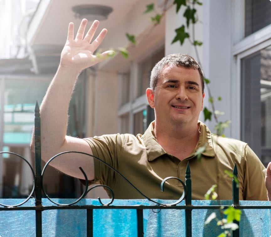 Smiling homeowner waving over a finished fence — flexible financing available